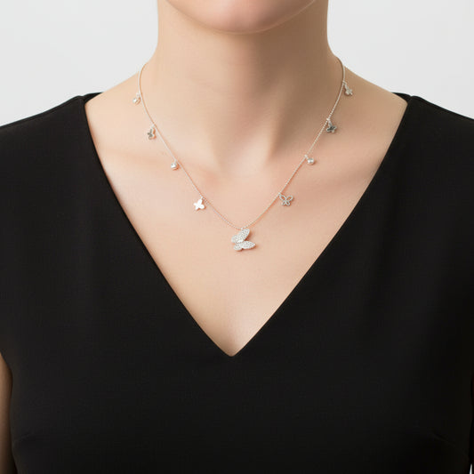 Silver necklace with butterfly pendants on a dark background, featuring the brand 'Saheli'.