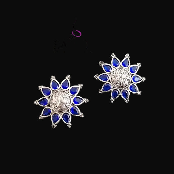 Silver and blue floral earrings on a gray background with 'Saheli' branding.