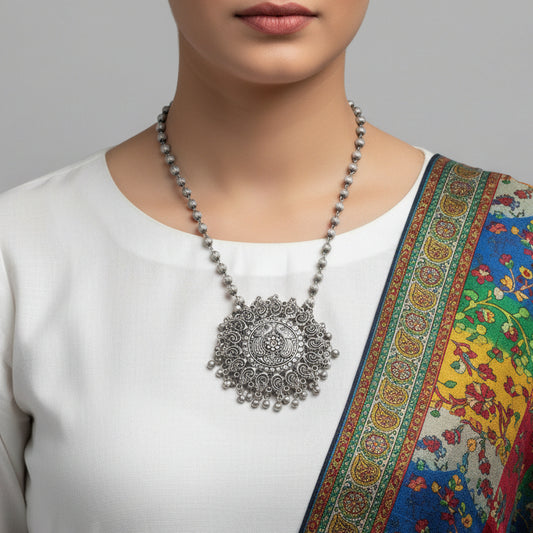 Silver necklace with intricate pendant on a gray background