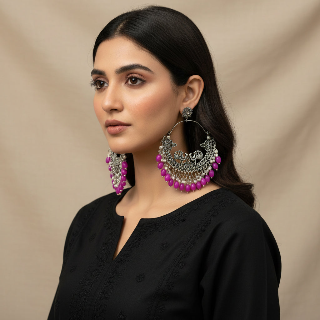 Silver hoop earrings with pink beads on a dark background