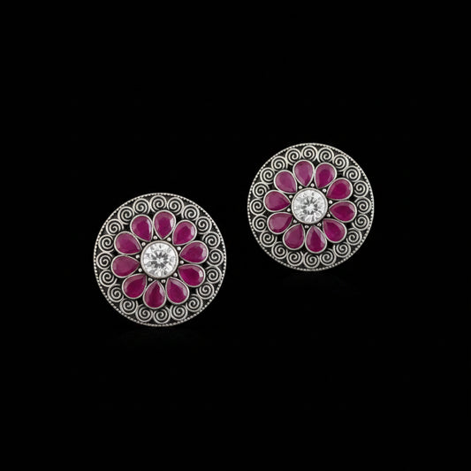 Pair of floral earrings with pink petals and a central gemstone on a gray background, branded 'SAHELI'.