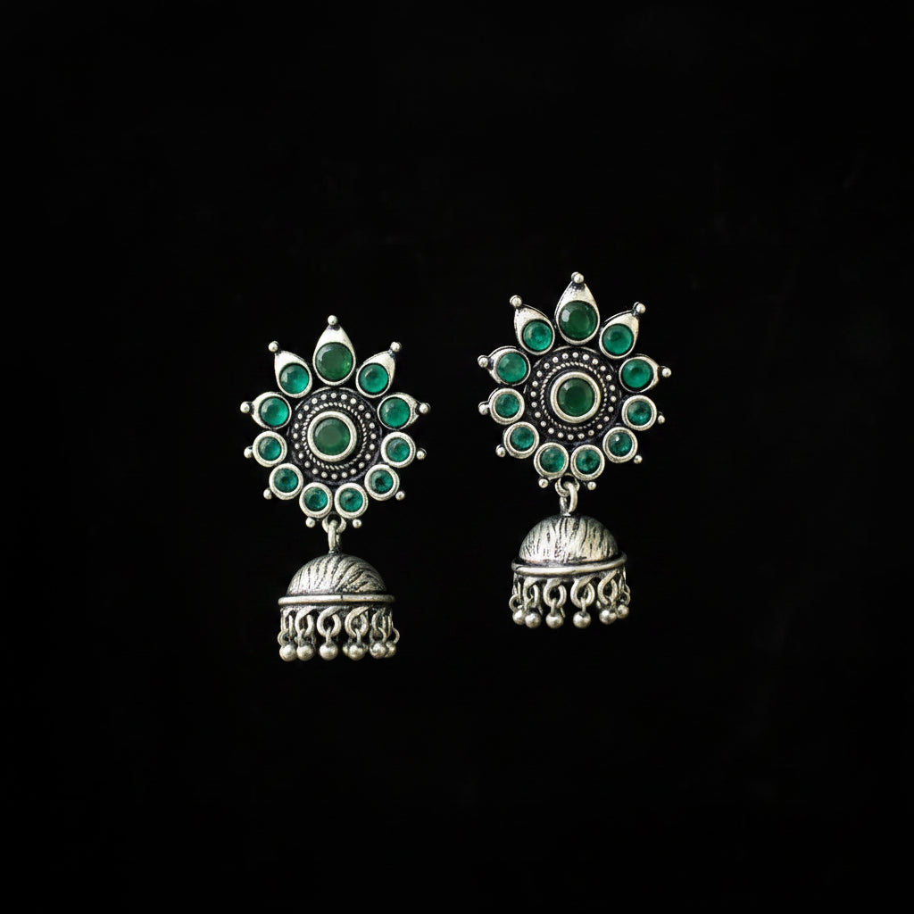 Pair of silver earrings with green gemstones on a black background