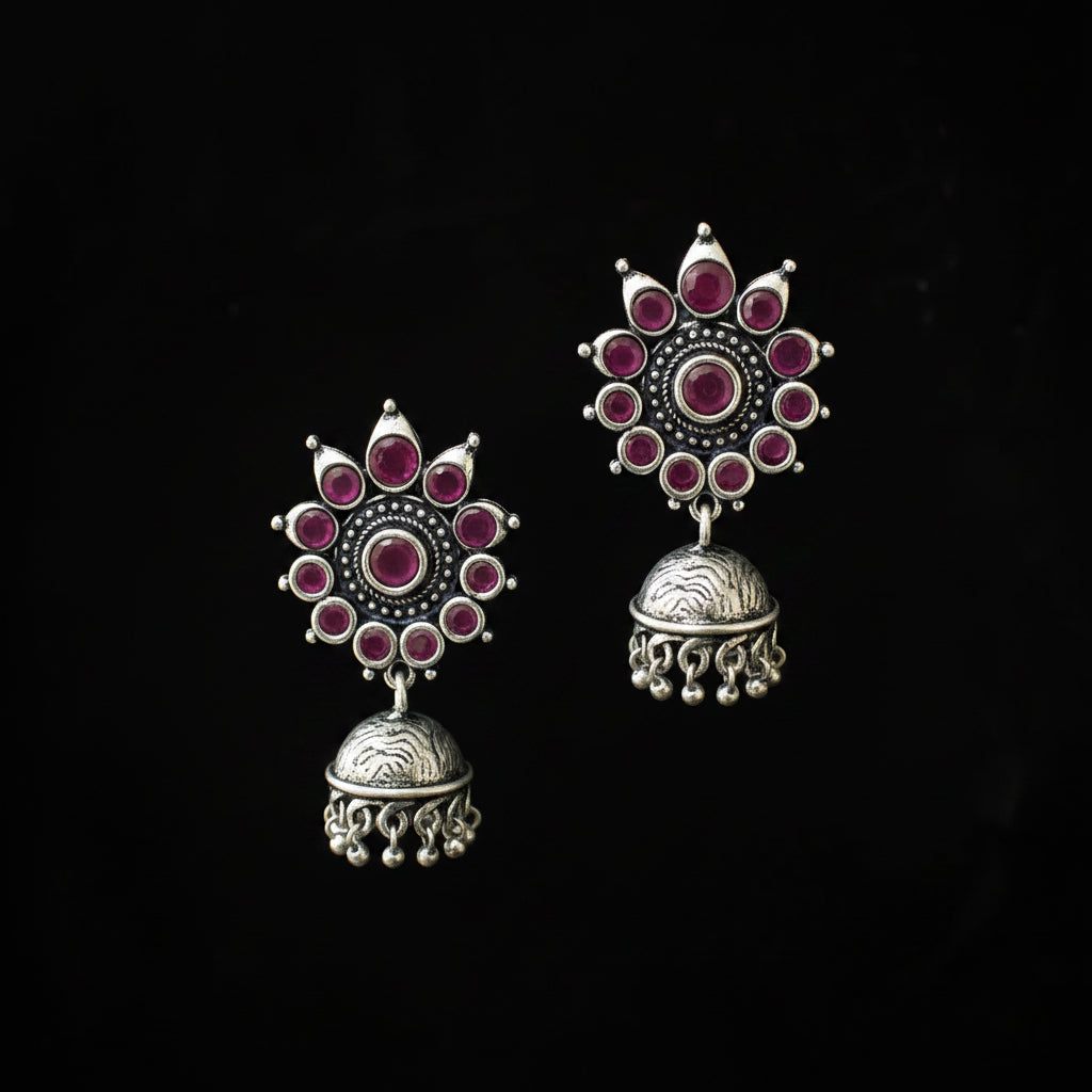 Pair of silver earrings with red gemstones on a black background
