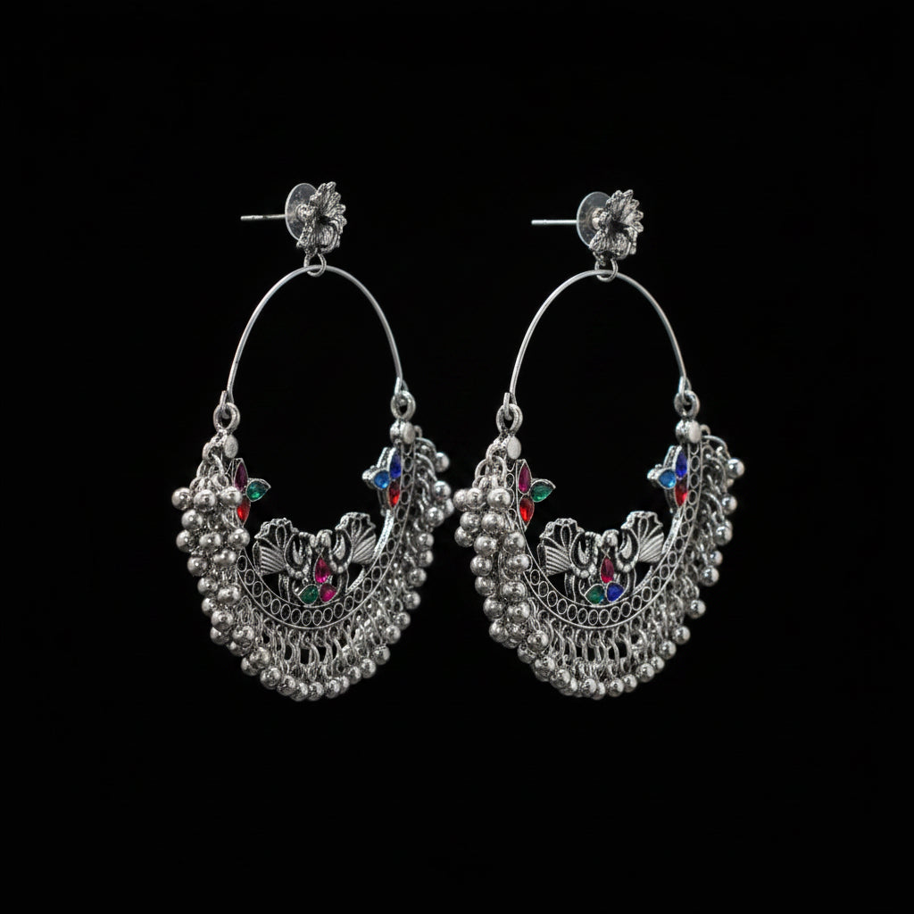 Pair of silver hoop earrings with colorful gemstones on a gray stand against a dark background