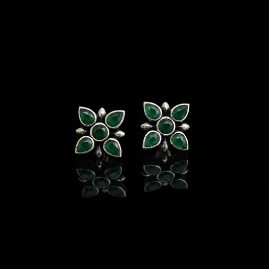 Pair of green and silver flower-shaped earrings on a dark gray background