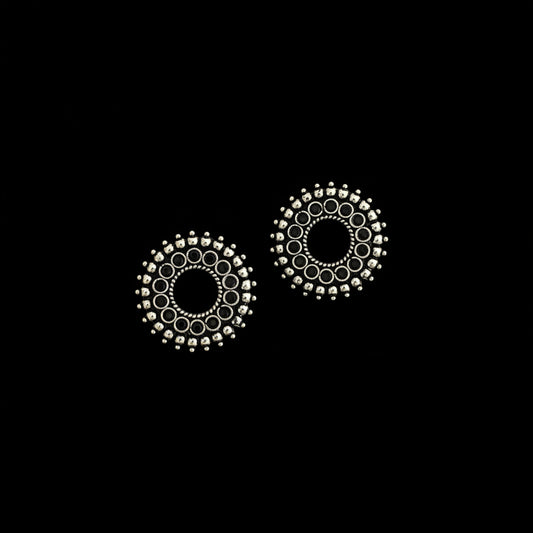 Pair of silver circular earrings on a dark background