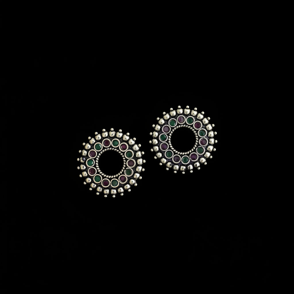 Pair of round earrings with colorful gemstones on a dark background