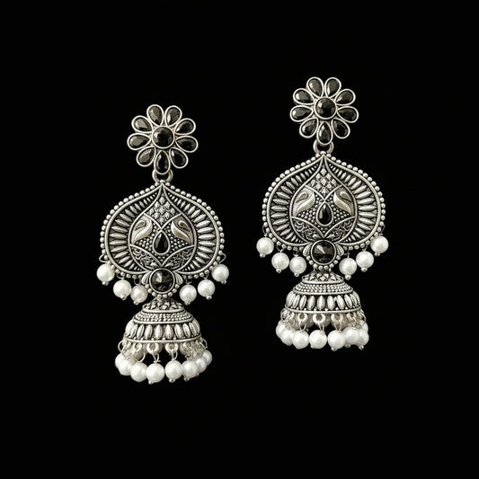 Pair of silver earrings with floral designs and pearl beads on a gray background