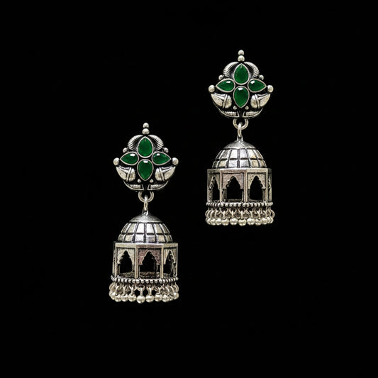 Pair of silver and green earrings on a black stand with a gray background