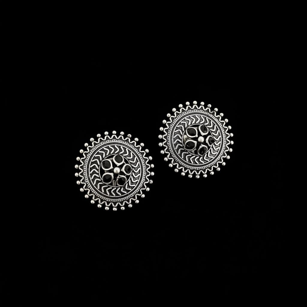Pair of silver earrings with intricate designs on a dark surface
