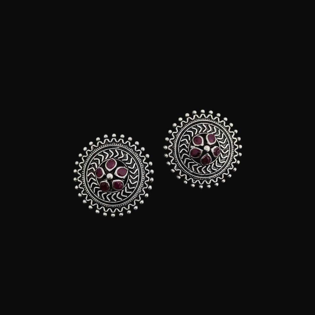 Pair of silver earrings with pink gemstones on a dark surface