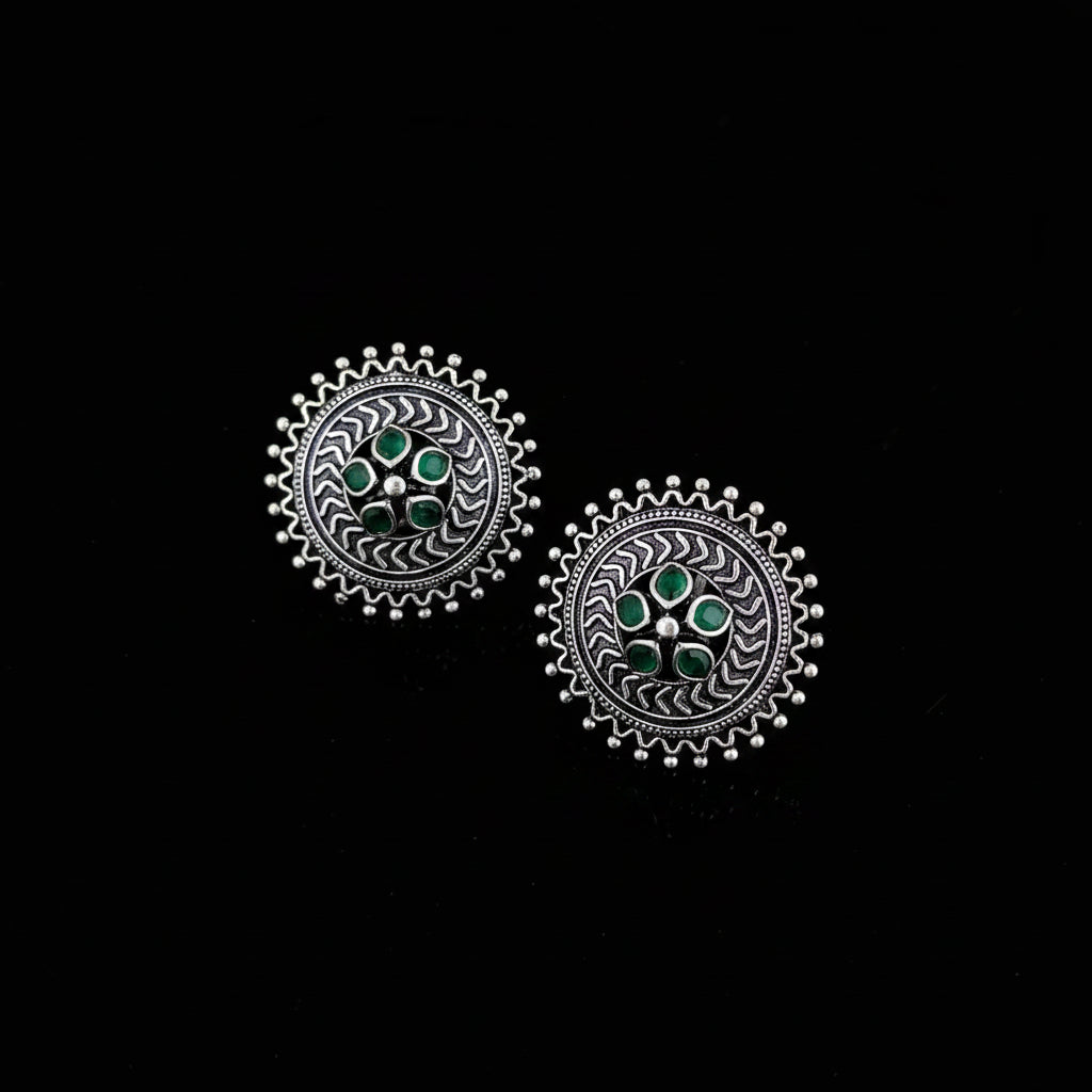 Pair of silver earrings with green gemstones on a dark surface
