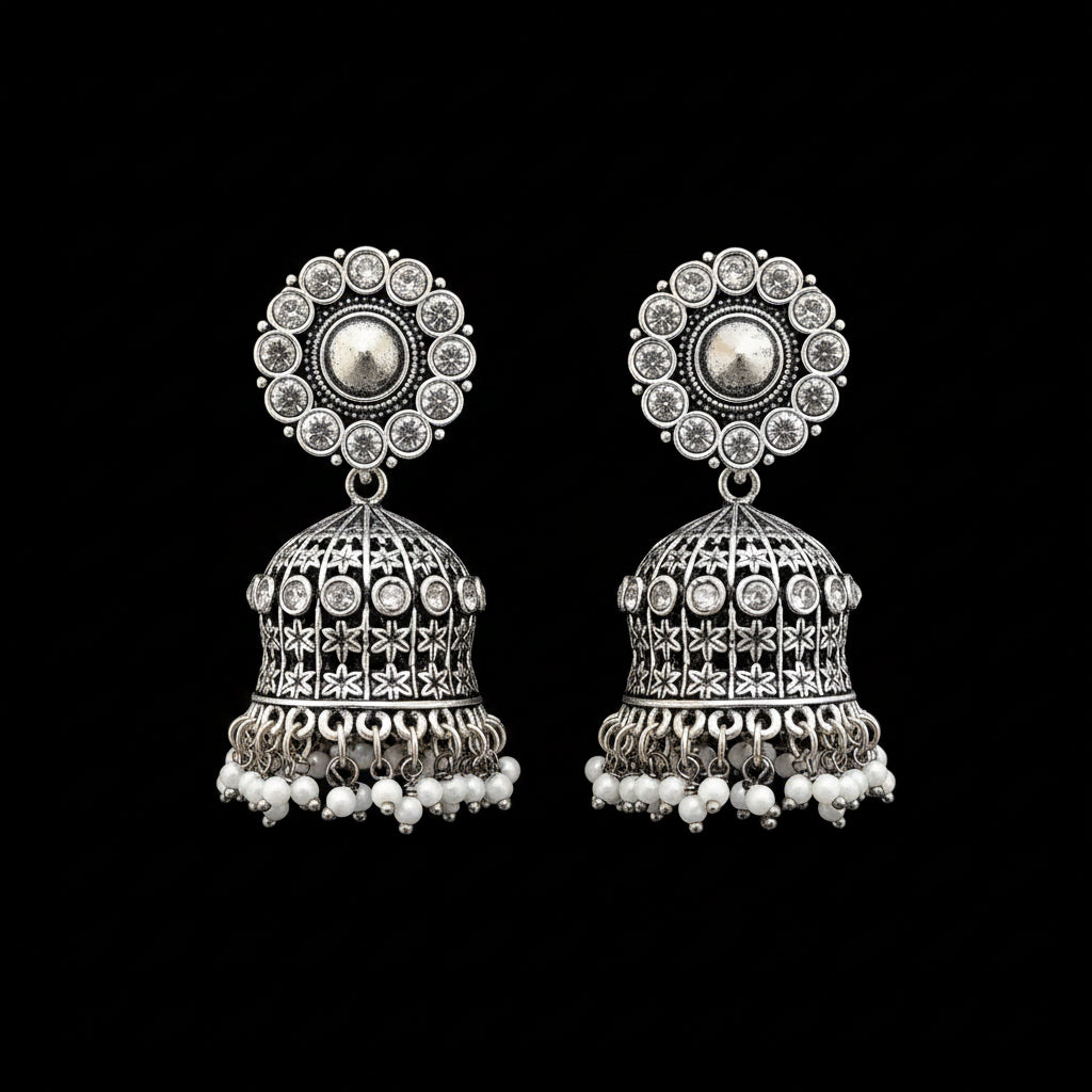 Pair of silver jhumka earrings with white beads on a gray stand.