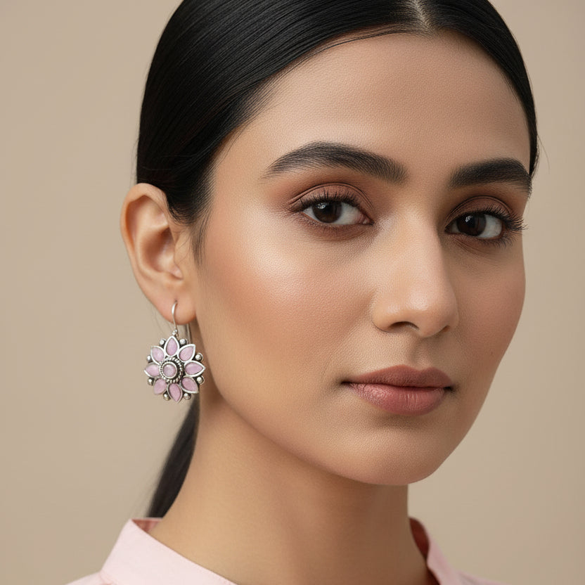 Pink flower-shaped earrings on a gray stone surface