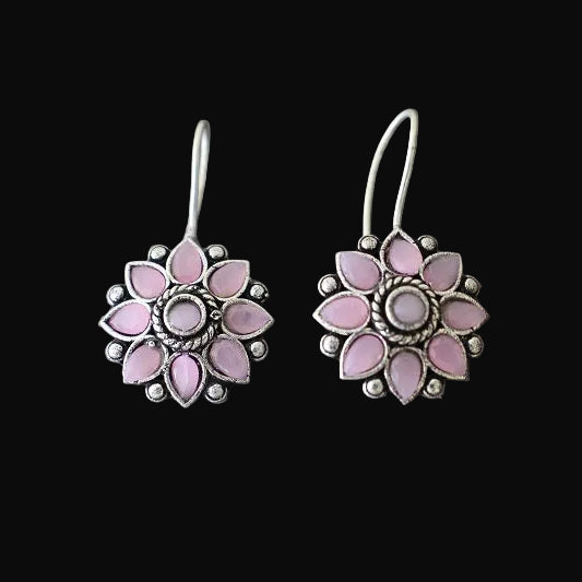 Pink flower-shaped earrings on a gray stone surface