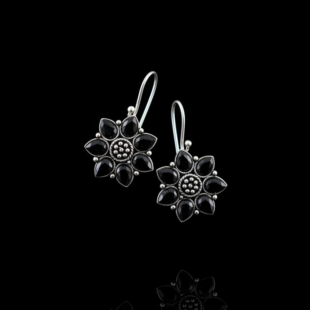 Pair of silver flower-shaped earrings on a gray cushion with a gray background