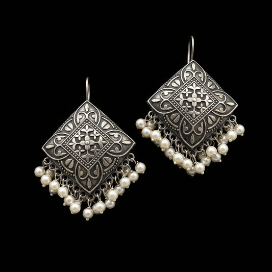 A pair of silver-toned geometric dangle earrings with intricate filigree cutouts and cascading pearl-like beads, displayed on a clean white background with the brand logo 'SAHELI MY BEST FRIEND' at the top.