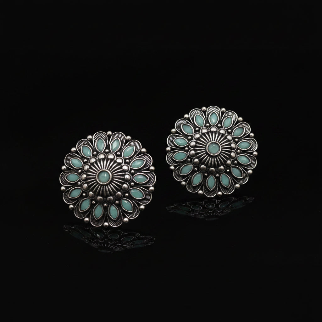 A pair of silver-toned circular concho-style earrings with turquoise blue inlay, displayed on a clean white background with the brand logo 'SAHELI MY BEST FRIEND' above them.