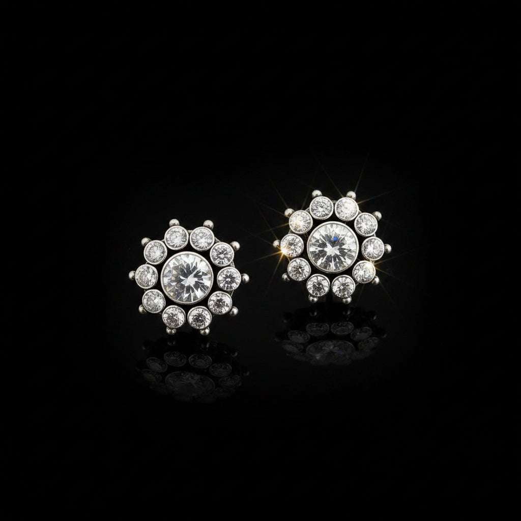 A pair of silver-toned stud earrings with clear round-cut gemstones arranged in a floral or snowflake-like cluster, displayed on a dark reflective surface with the SAHELI MY BEST FRIEND logo above.