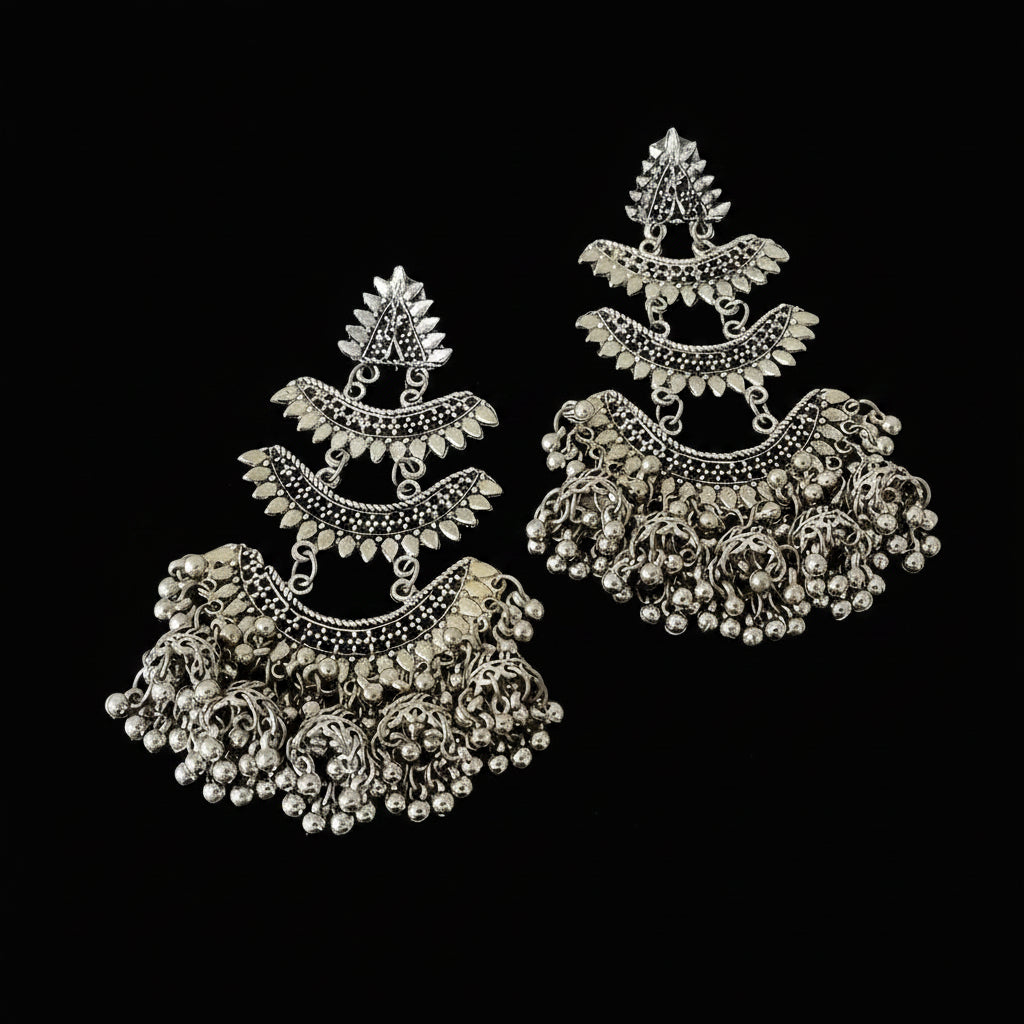 Pair of silver earrings with intricate designs on a dark background, branded 'Saheli'.