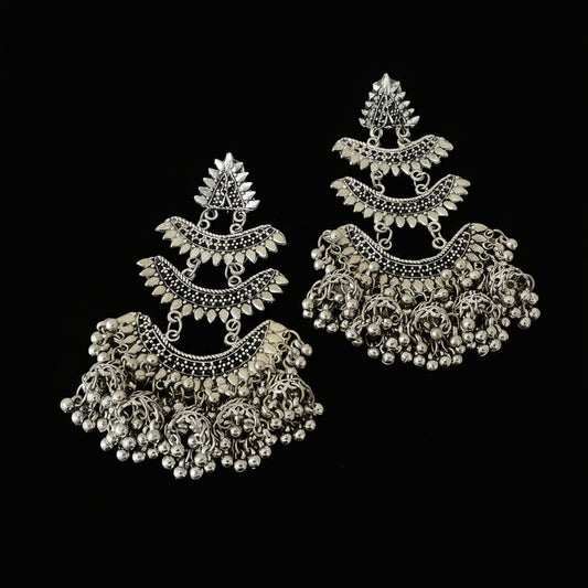 Pair of silver earrings with intricate designs on a dark background, branded 'Saheli'.