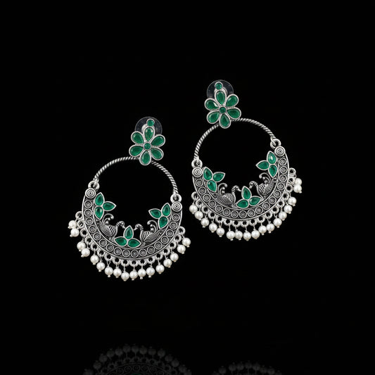 Pair of silver earrings with green floral designs on a black background