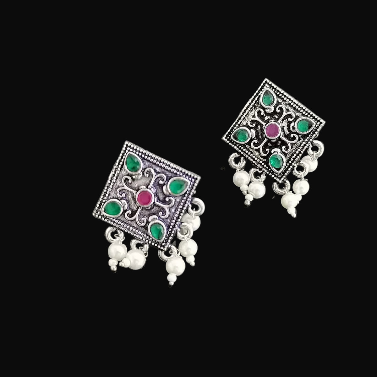 Pair of silver earrings with gemstones and pearls on a dark gray background