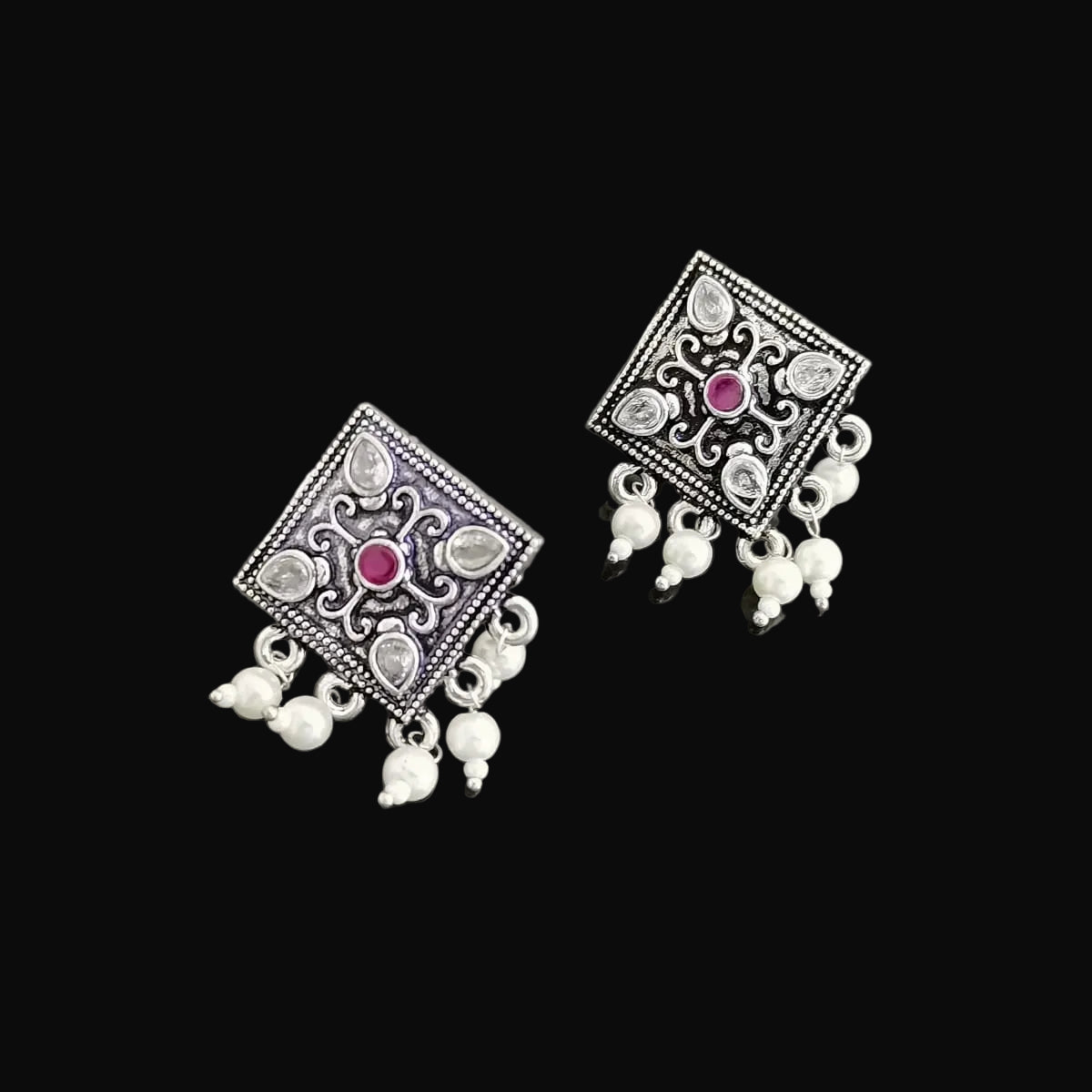 Pair of silver earrings with gemstones on a gray background