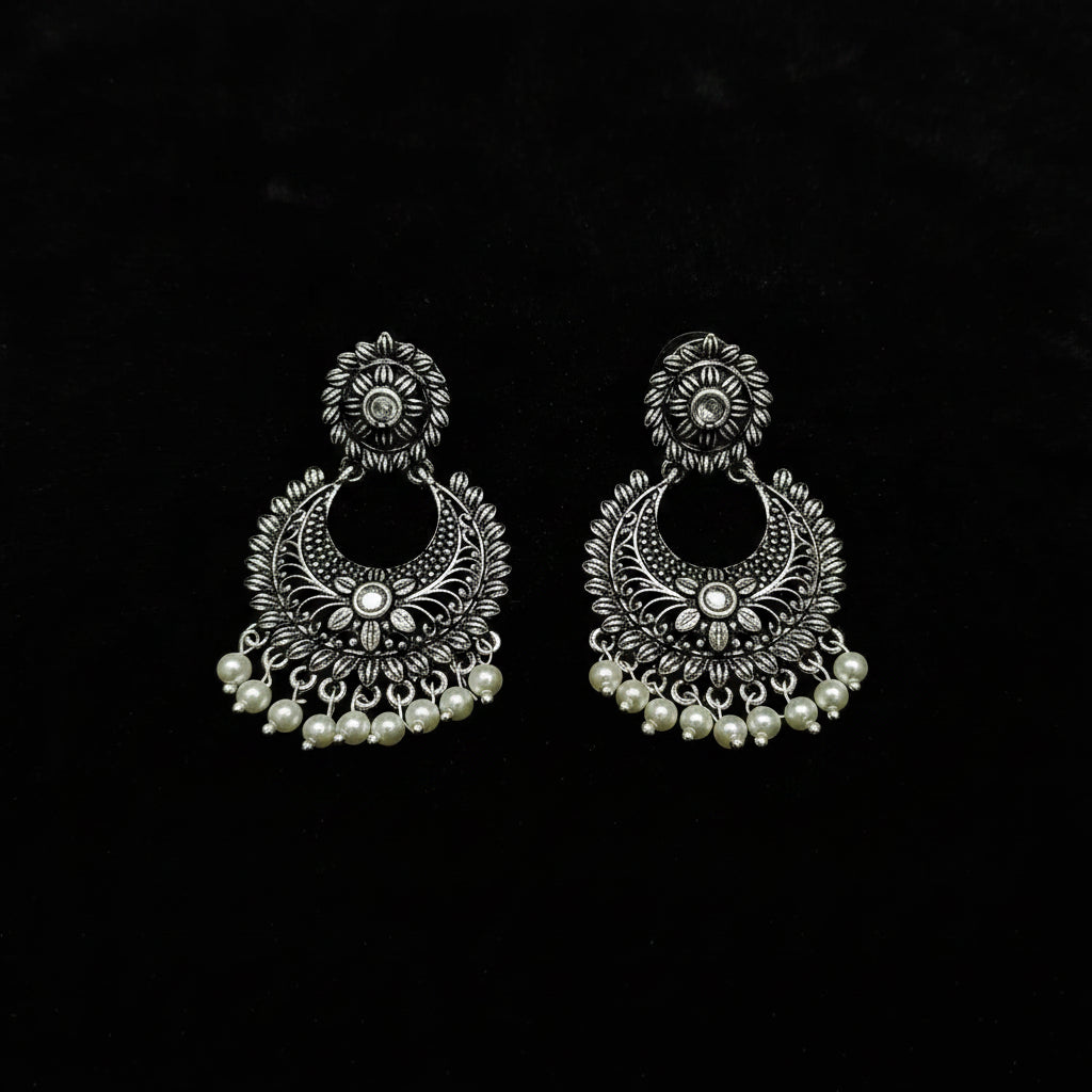Pair of silver earrings with pearl accents on a black background