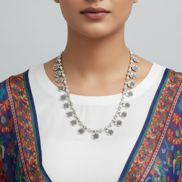 Silver floral necklace on a reflective surface