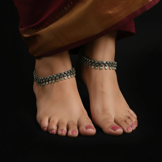 Silver necklace and bracelet set with 'Saheli' branding on a dark background