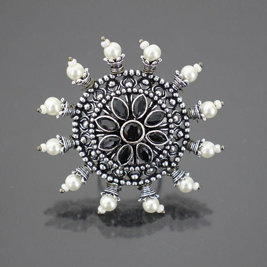 Decorative silver brooch with pearl-like stones on a gray background
