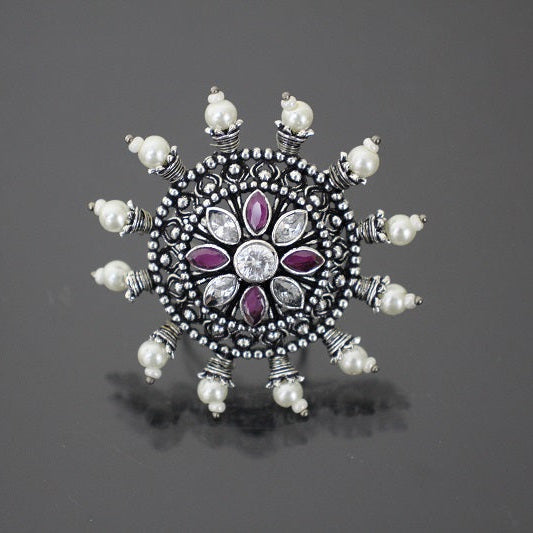 Decorative silver brooch with purple gemstones on a gray background
