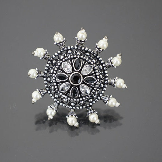 Decorative silver brooch with pearl-like stones on a gray background