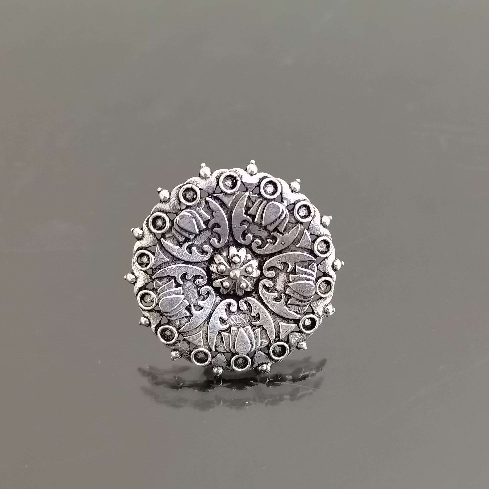 Silver ring with intricate design on a gray background