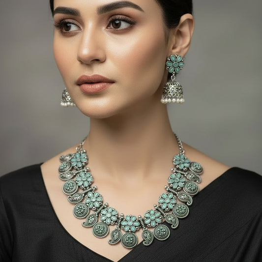 Silver necklace with floral designs and matching earrings on a gray background