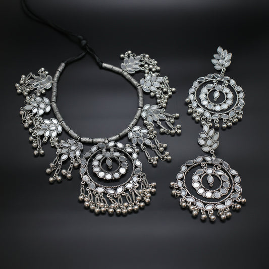 Silver necklace and earrings on a dark background
