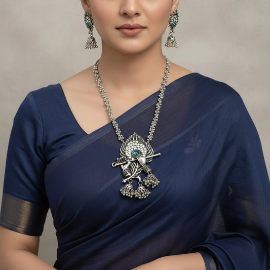 Silver necklace and earrings set with intricate designs on a dark background