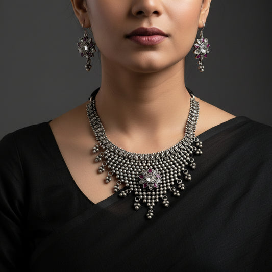 Silver necklace and earrings with 'Saheli' branding on a gray background