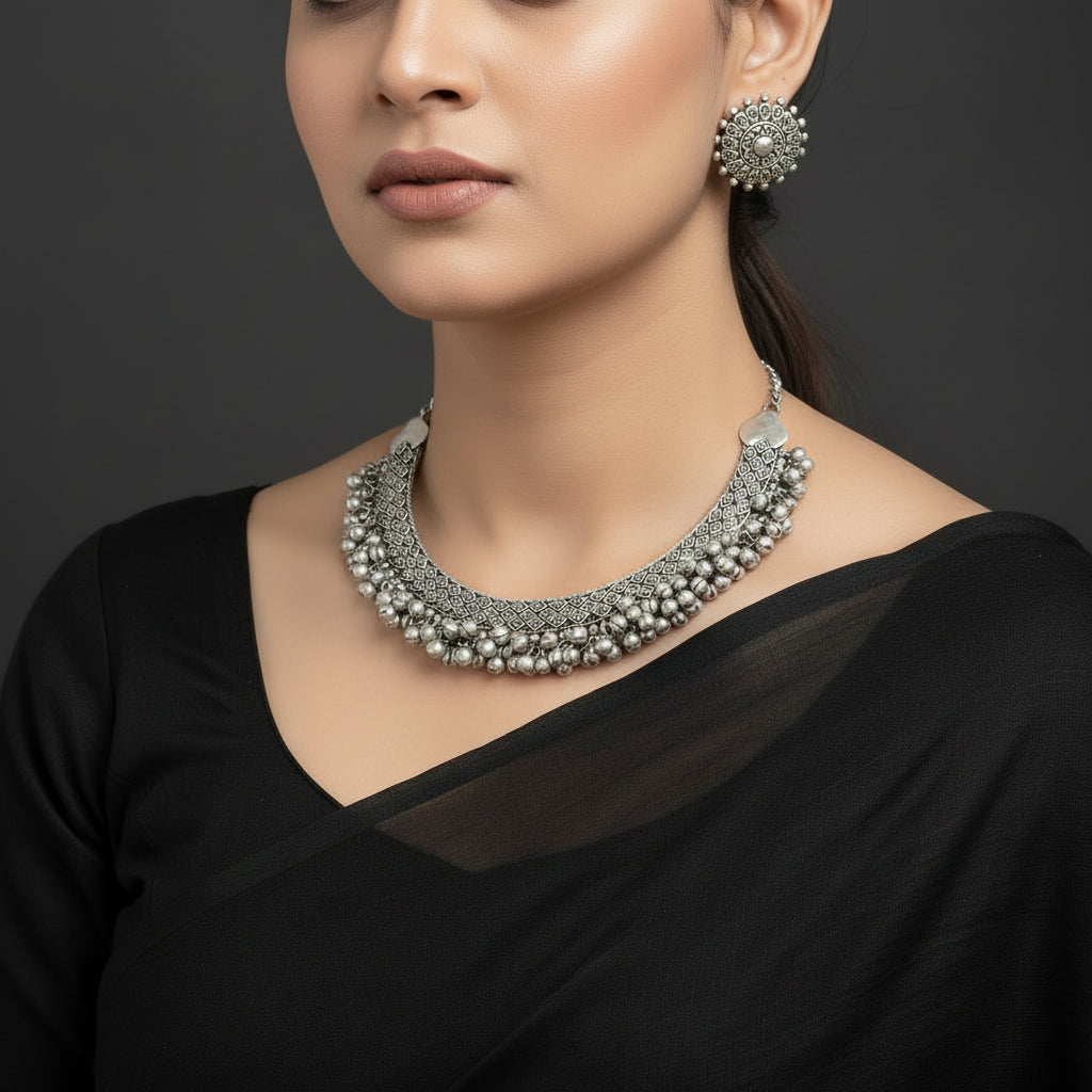 Silver necklace and earrings set with 'Saheli' brand logo on a dark background