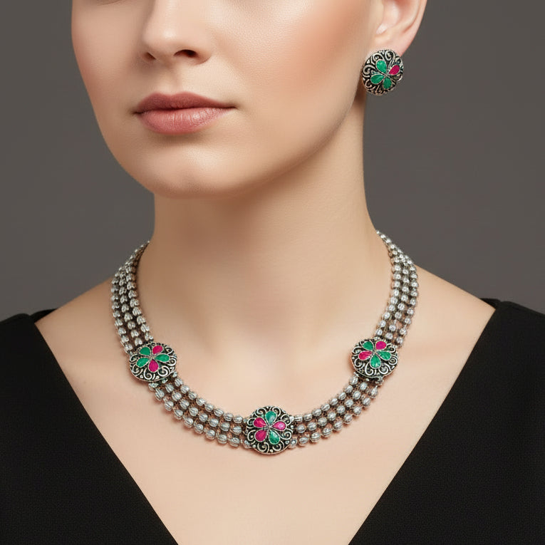Jewelry set with necklace and earrings on a reflective surface, featuring the brand 'Saheli'.