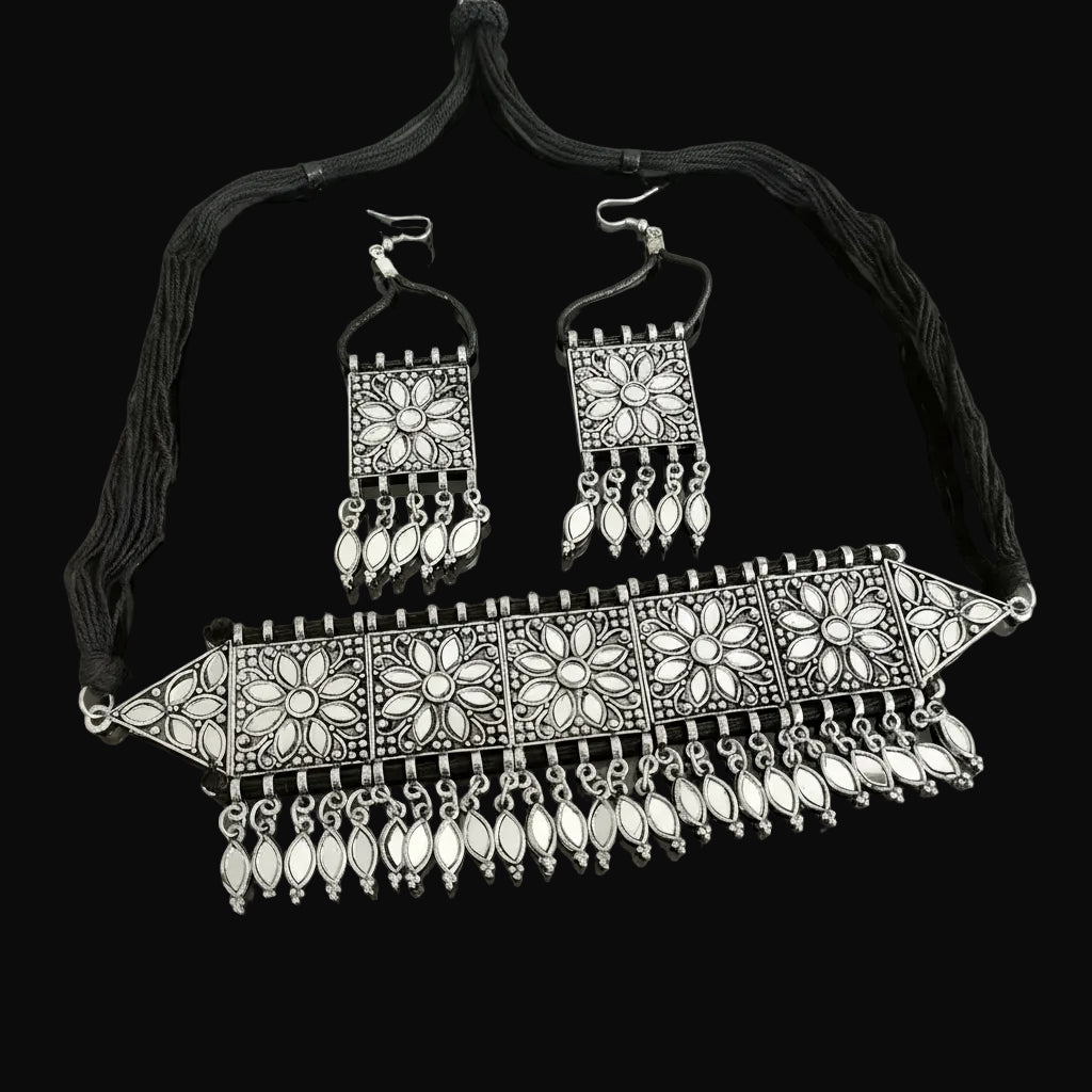 Ornate silver necklace and earrings set with 'Saheli' branding on a dark background