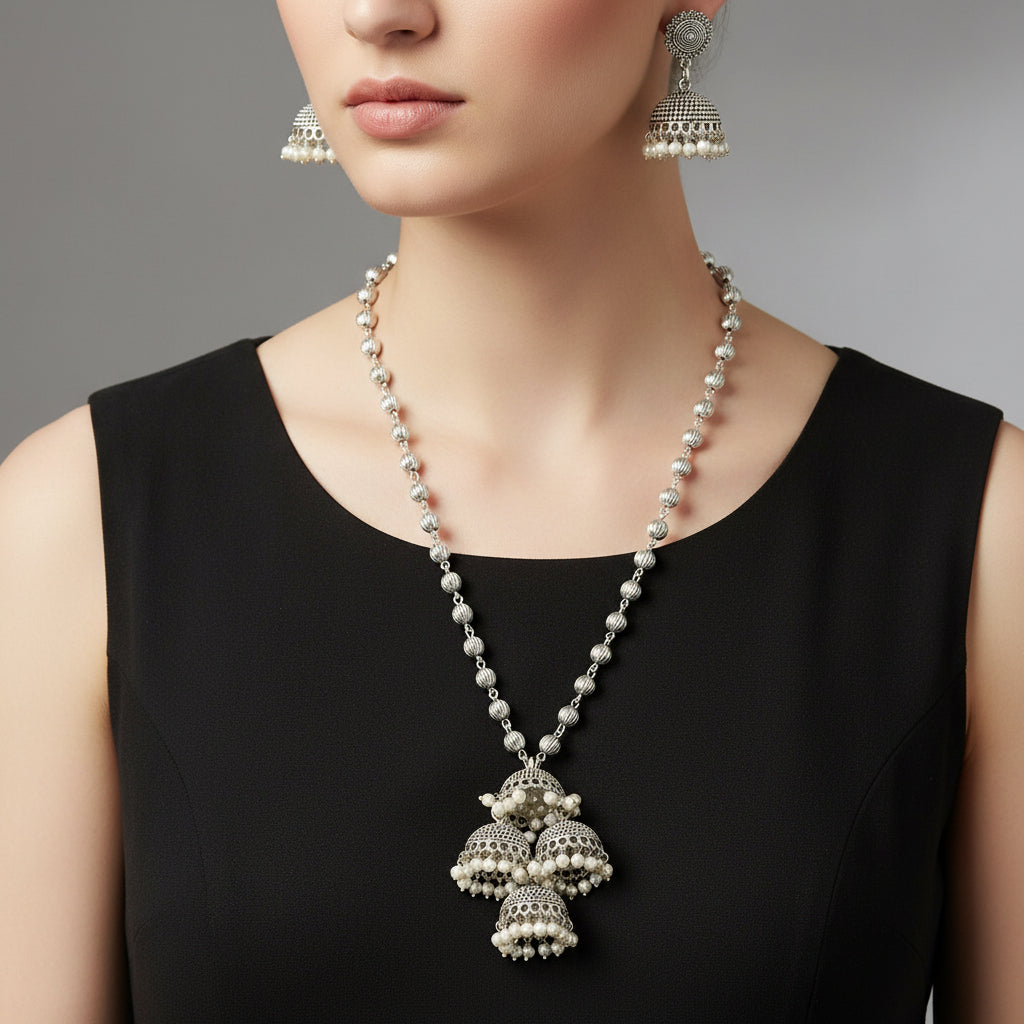 Silver necklace with pendant and earrings on a gray background, featuring the brand 'SAHELI'.