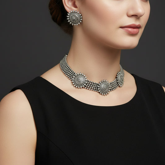 Silver necklace and earrings set with 'Saheli' branding on a gray background
