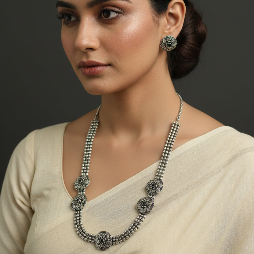 Silver necklace and earrings on a dark background