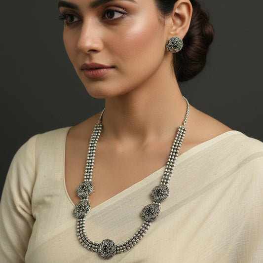 Silver necklace and earrings on a dark background