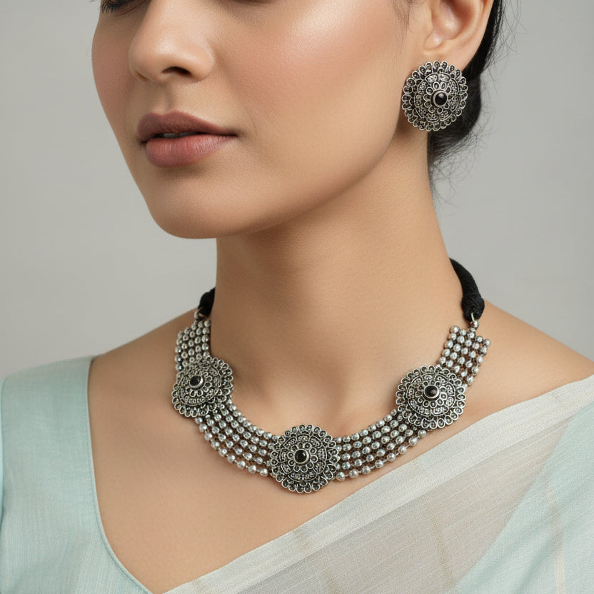 Silver necklace and earrings set on a dark surface