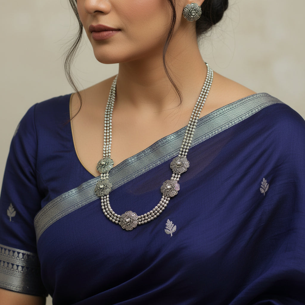Silver necklace and earrings on a dark surface