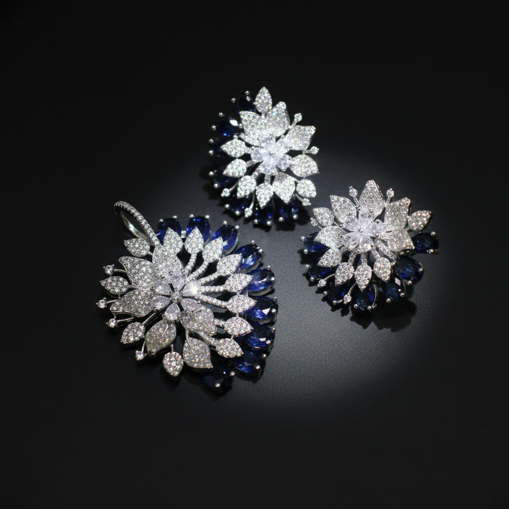 Three floral-shaped jewelry pieces with blue and clear gemstones on a dark background