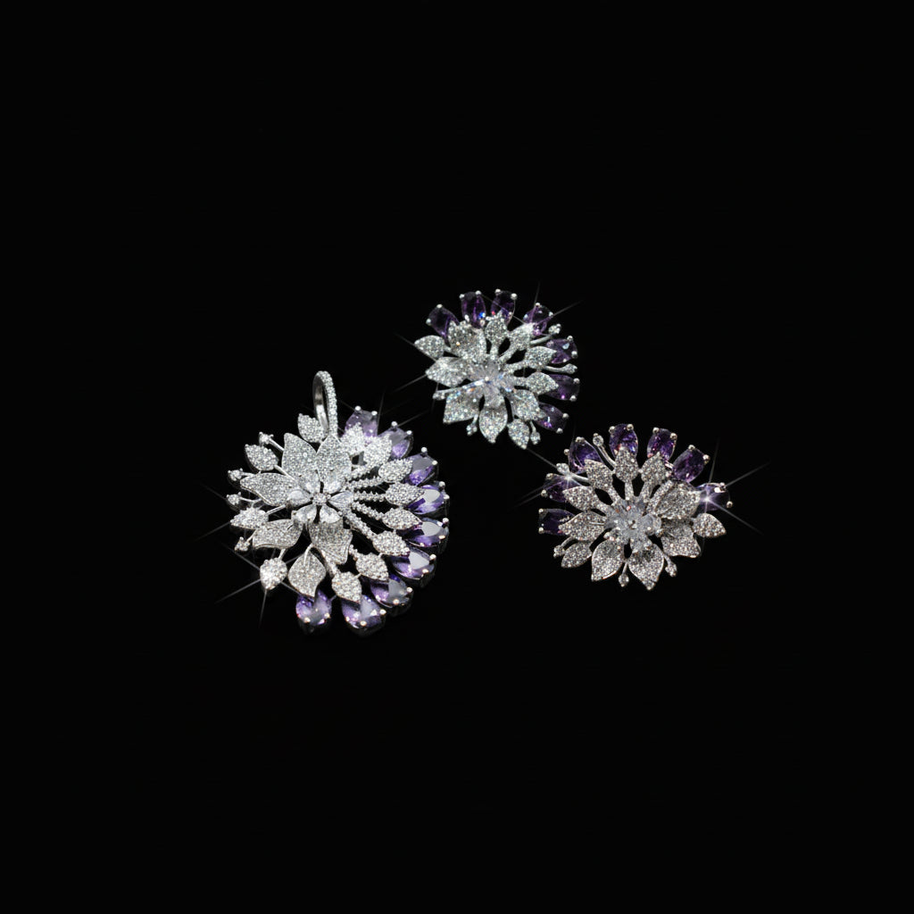 Three floral-shaped jewelry pieces with purple stones on a gray background